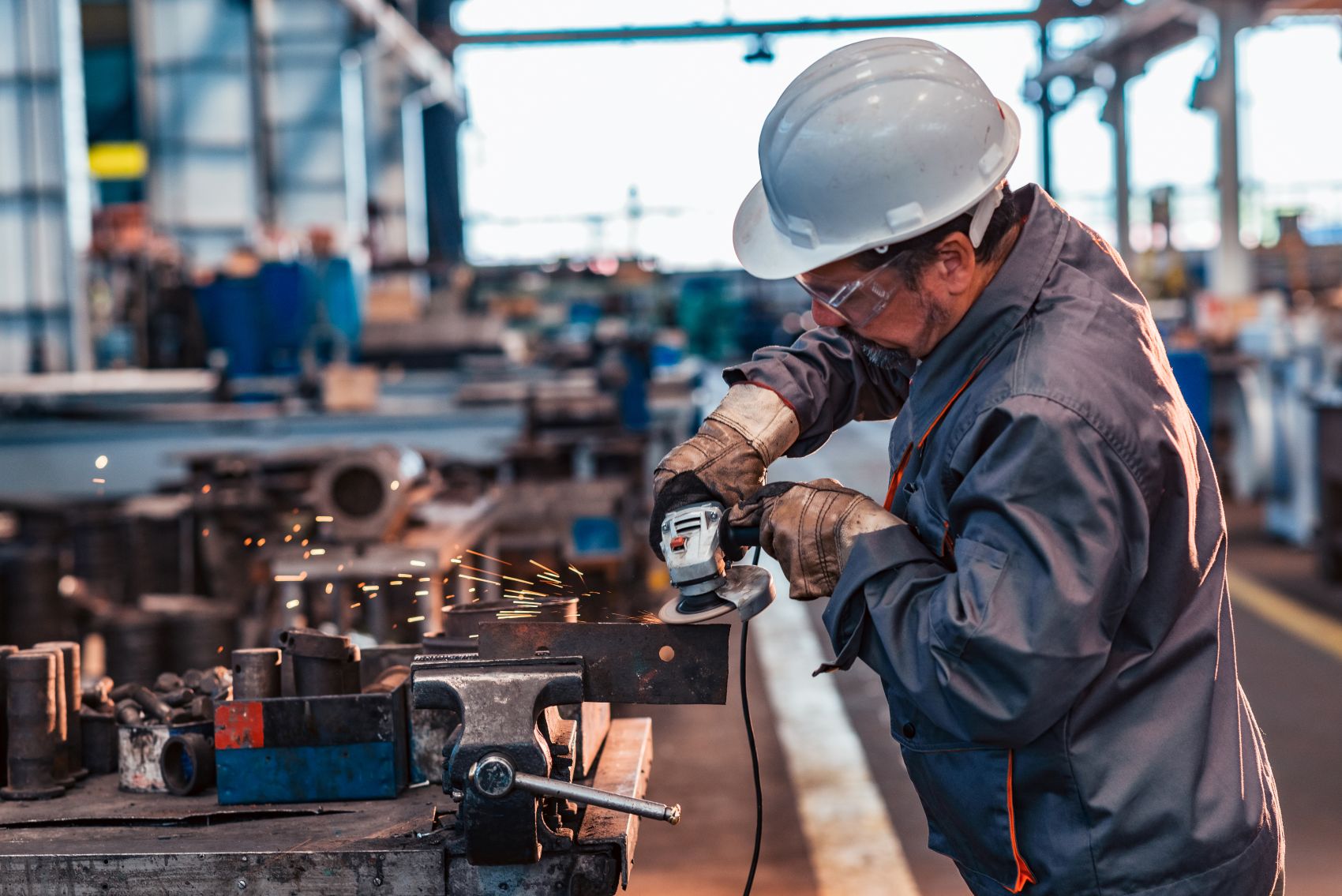 Worker grinding metal in a manufacturing facility
